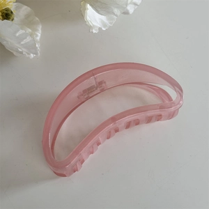 Détail d'une pince à cheveux demi-lune rose mat avec ressort métallique robuste