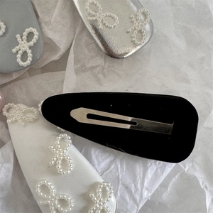 Dettaglio di fermagli per capelli con fiocco di perle, texture in pelle e clip in metallo