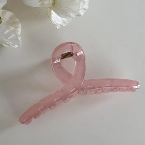 Détail de la pince à cheveux rose translucide avec design croisé et ressort en métal