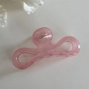 Détail macro de la pince à cheveux rose translucide avec un ressort métallique robuste