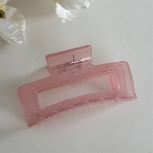 Détail d'une pince à cheveux rectangulaire rose translucide avec un ressort en métal
