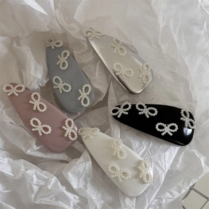 Dettaglio di cinque fermagli BB in pelle colorata con eleganti fiocchi di perle bianche
