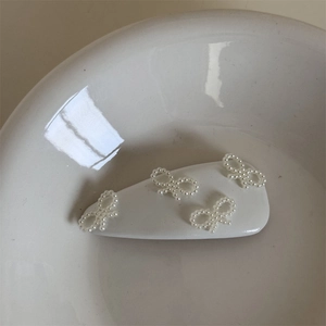 Dettaglio di un fermaglio per capelli bianco con tre piccoli fiocchi di perle