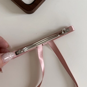 Detail view of pink satin hair clip with a smooth silver metal spring clip fastener