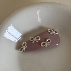 Dettaglio di un fermaglio per capelli in pelle rosa con fiocco e perle in una ciotola ceramica