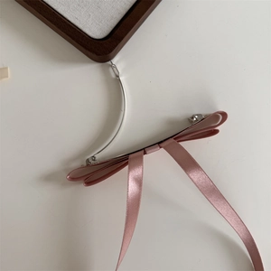 Detailed back view of pink satin ribbon hair clip showing the silver metal spring mechanism