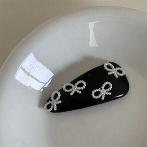 Dettaglio di fiocchi di perle su fermaglio nero a goccia su piatto di ceramica