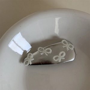 Dettaglio di quattro fiocchi in perle finte su un fermaglio per capelli in metallo argento