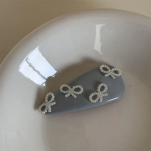 Dettaglio di un fermaglio grigio con fiocchi di perle bianche in una ciotola di ceramica bianca