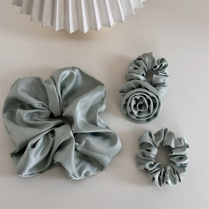 Vue détaillée de trois chouchous en satin vert avec tissu en soie et décor floral