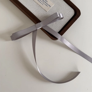 Detailed view of ballet-style gray satin bow hair clip with long ribbons on display
