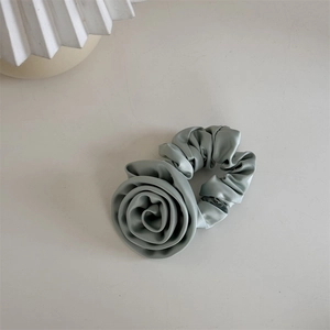Détail du chouchou en satin vert sauge avec grand motif floral de rose en 3D