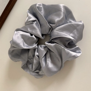 Detailed view of silver grey satin scrunchie showing soft fabric texture and elegant folds