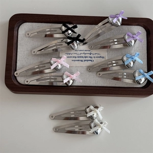 Silver alloy heart bow BB hair clips in five colors set on a vintage wooden tray
