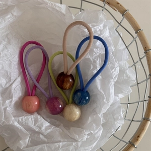 Détail de cinq perles en résine marbrée sur des élastiques à cheveux dans un panier