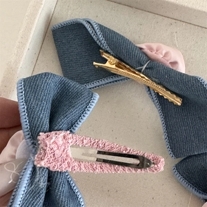 Detail of blue denim rose hair clips with pink lace trim and metallic back fasteners