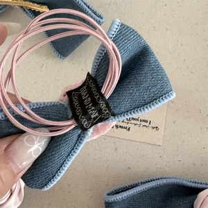 Close-up of blue corduroy bow hair tie with pink multi-strand elastic band