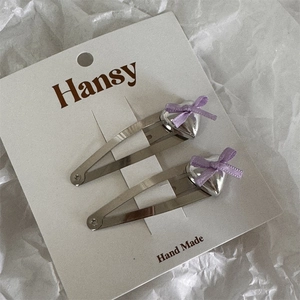 Detail of silver heart hair clips with purple ribbon bows on display card
