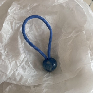 Détail d'un élastique à cheveux bleu avec une perle en résine marbrée et texture nervurée