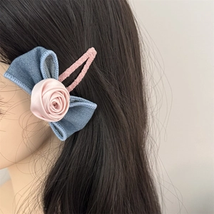 Blue denim bow hair clip with pink rose and lace metal base worn on model's hair