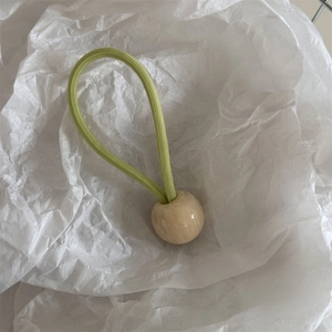 Détail d'élastique à cheveux vert clair avec perle décorative texture marbre blanc