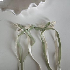 Detail von eleganten zweifarbigen Satin-Haarschleifen mit langen Bändern in Creme und Salbei