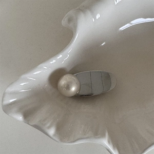 Détail macro d'une élégante pince à cheveux en métal argenté avec perle sur plat