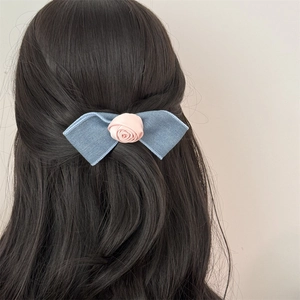 Blue denim bow hair clip with a pink satin rose flower shown on long brown hair