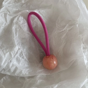 Détail d'élastique rose avec perle en résine marbrée sur fond de papier froissé blanc