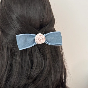 Detailed back view of a blue denim bow hair clip with a pink satin rose on long hair