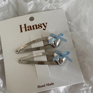 Close-up of silver alloy heart bow hair clips on a white display card minimalist style