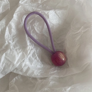 Détail d'élastique à cheveux violet avec perle en résine marbrée sur papier