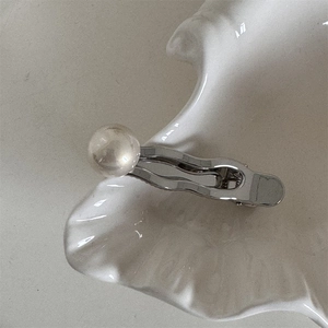 Vue détaillée de la pince à cheveux argentée avec une grande perle ronde blanche