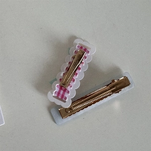 Detail view of pink plaid bow hair clip with wavy lace edge and golden alloy metal base