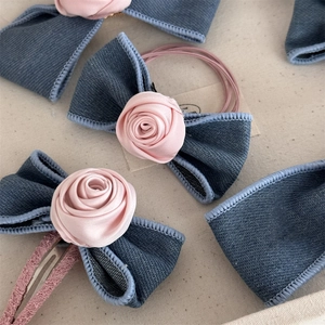 Detailed close-up of handmade denim rose bow hair clip with pink lace and satin accents