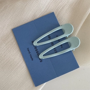 Dettaglio di fermagli per capelli a goccia verde chiaro opaco su carta blu