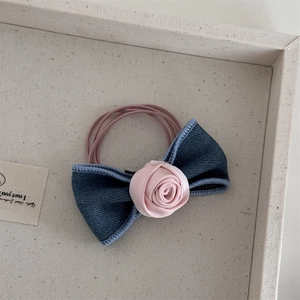 Detailed close-up of blue denim bow hair tie with a pink satin rose and elastic bands