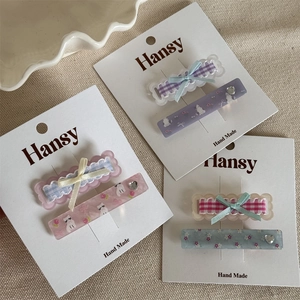 Detail view of plaid bow hair clips and cat floral printed resin clips with heart rhinestones