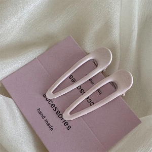 Dettaglio di due fermagli per capelli in metallo rosa loto opaco a forma di goccia d'acqua