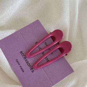 Primo piano di due fermagli per capelli a goccia color prugna su cartoncino viola