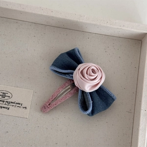Detail of a French-style hair clip featuring a pink satin rose and blue fabric bow