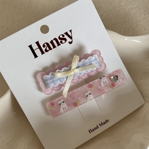 Close-up of cute floral cat hair clips with plaid ribbons and heart rhinestone details