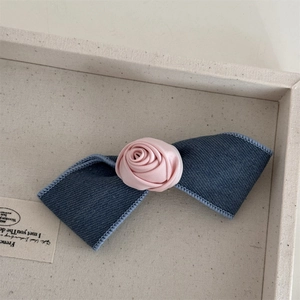 Detailed macro view of the denim fabric bow and handmade pink satin rose hair clip