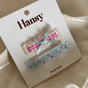 Detail of pink plaid bow hair clip and blue floral clip with heart rhinestone