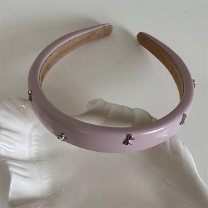 Détail d'un serre-tête en cuir rose avec nœuds en métal argenté sur plateau en coquillage