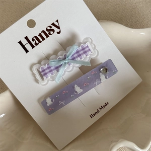 Detail of cute cat and floral pattern hair clips with purple ribbon on a porcelain plate