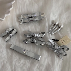 Kit barrettes nœud en similicuir argenté avec strass cœur sur plateau blanc