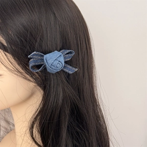Blue denim rose hair clip with yellow stitching detail on black hair for women