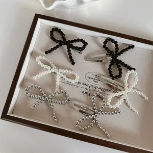 Detail view of handmade beaded bow hair clips in black, white pearl, and silver metallic