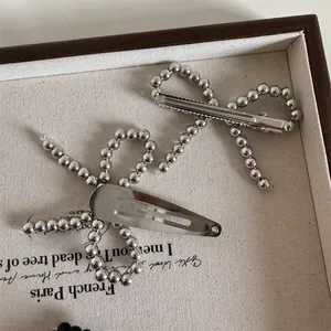 Detail view of a silver beaded bow hair clip set with alligator and snap-on styles